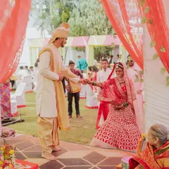 The groom leads his bride during the wedding rituals. This shot captures the traditional elements and the couple's first steps together, framed by the vibrant decor of the mandap.