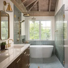A luxurious master bathroom in our Saratoga project, designed to feel like a private spa. The freestanding tub sits under a large window, and the walk-in shower is lined with beautiful green tiles. The vaulted wood ceiling adds a final touch of rustic warmth.