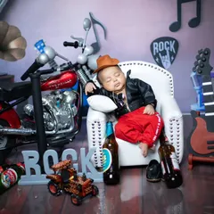 Another angle of our little rockstar, showing off the full setup with a miniature motorcycle and 'ROCK' sign. I pay attention to every detail to make the concept feel complete and fun.