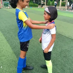 True strength lies in lifting others up. An older player congratulates a younger teammate, showcasing the spirit of our girls' program.