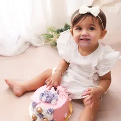 A sweet smile and a messy face. This little girl is enjoying her first birthday cake in our lovely boho-themed setup. The combination of the pink cake and her white dress is simply adorable.