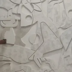 A close-up of a large-scale plaster mural during its creation. This shot reveals the process of hand-sanding the raised abstract forms, highlighting the tactile quality and craftsmanship that goes into each of our textural wall pieces.