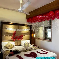 A simple yet beautiful birthday surprise setup in a hotel room. It includes a "Happy Birthday" banner, "love" foil balloon, and a bed decorated with rose petals and towel swans.