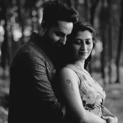 An intimate embrace captured in moody black and white. The soft focus and deep shadows of the forest create a sense of privacy and deep connection.