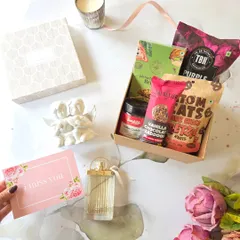 This romantic hamper is perfect for a cozy celebration. It features vanilla chocolate laddoos, pretzels, and a scented candle, paired with a perfume bottle and a sweet "I miss you" card.