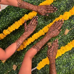 A creative shot of multiple hands displaying their detailed henna designs against a decorative backdrop.