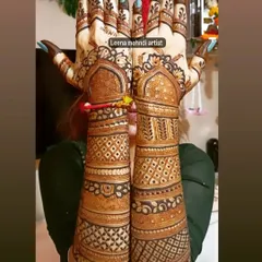 A stunning example of full-coverage bridal mehndi held up for a complete view. The design features classic Indian motifs with geometric patterns filling the arms, creating a beautiful contrast.