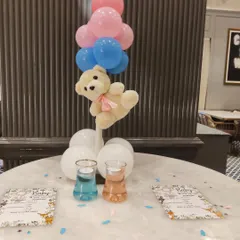 This teddy bear centerpiece is perfect for guest tables at a baby shower. The floating bear is carried by a bunch of pink and blue balloons, with themed stationery and confetti scattered on the table to complete the look.