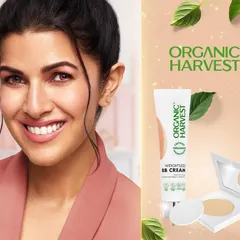 A campaign photograph featuring actress Nimrat Kaur for Organic Harvest. This shot combines a warm, approachable portrait with product imagery for their BB cream and compact, creating an authentic celebrity endorsement for a natural cosmetics brand.