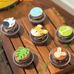 For a child's party, I created these jungle-themed cupcakes. Each chocolate cupcake has a custom-made fondant topper, including a tiger, monkey, zebra, and monstera leaf, showcasing my detailed character work.