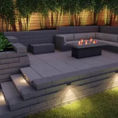 This is a closer look at a modern backyard design featuring a cozy seating area with a fire pit. The multi-level hardscaping with built-in lighting creates a sophisticated ambiance, perfect for evening gatherings.