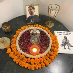 A sacred corner of our shala, with a photo of my Guru, an Ashtanga manual, and offerings of flowers and light. This space holds the intention and reverence for our practice.