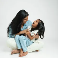 A mother tickles her daughter, both lost in a moment of playful joy. Studio sessions with me are relaxed, allowing for natural interactions and genuine smiles.