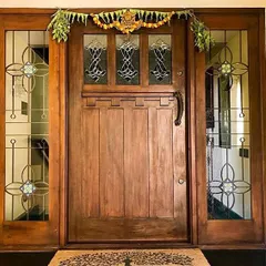 This solid wood entrance door, framed by glass panels with traditional motifs, offers a grand welcome to the Roopa Hariprasad Residence. The design balances strength and elegance, reflecting the home's blend of modern and classic styles.