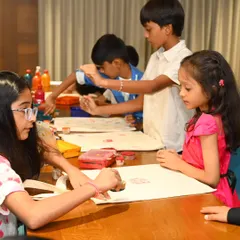 A group of children are completely absorbed in a tote bag painting activity, using stamps and brushes to create their designs. Our workshops for kids are designed to be engaging, fun, and a great way for them to express their creativity.