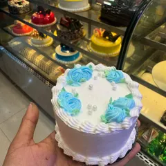 Another one of our charming mini cakes, this one is decorated with delicate blue buttercream roses and pearl-like sprinkles. It’s an elegant and simple treat for one or two people.