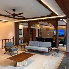 This angle showcases the blend of modern furniture with the traditional wooden framework in the Bengaluru apartment. The clean lines of the sofa and coffee table contrast beautifully with the ornate details of the pillars, creating a balanced and sophisticated interior.