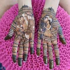 A beautiful and detailed design for an engagement, focusing on the couple's portrait on the palms. The fingers are tipped with fresh henna paste, ready for a deep, rich stain.