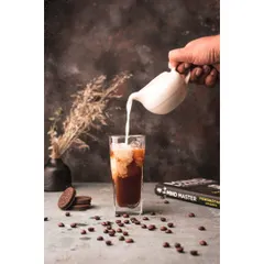 An action shot capturing the moment milk is poured into iced coffee. This dynamic style brings the beverage to life, creating a refreshing and engaging image for a cafe or social media.