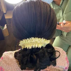 A close-up of a sleek low bun, neatly wrapped and adorned with a simple jasmine gajra.
