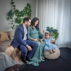 A serene family maternity portrait in my Boho studio. The family is seated together, with the focus on the mother's baby bump and the excitement of the older sibling.