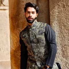 A modern interpretation of traditional thread work. This black Nehru jacket features a detailed print of heritage architecture and elephants, worn over a textured black kurta for a sophisticated, layered look.
