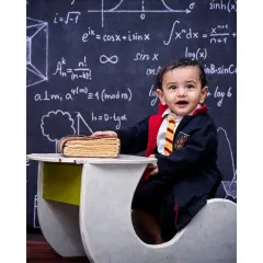 A happy future wizard, dressed in his house colors and sitting at a desk in front of a chalkboard of equations. This Harry Potter themed shoot is a great example of how I bring popular stories to life for your little one.