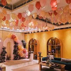 A full view of a stunning baby shower we designed. The room is filled with ceiling balloons in a warm color palette, leading to an elegant backdrop of arches, florals, and more balloons, creating a dreamy and immersive experience.