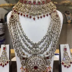 A magnificent layered bridal set with a large circular pendant, studded with ruby-colored stones and crystals for a royal look.