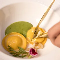 A delicate moment with our Truffle Fungi Cream Cheese Ravioli, part of the Holiday Feast. The filling is revealed, showcasing the rich, creamy texture inside.