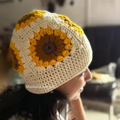 A side view of our sunflower crochet cap, showing the detailed granny square pattern. We use a blend of mustard, yellow, and white yarn to create this cheerful design, which is one of our bestsellers.
