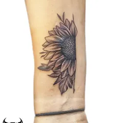 After: This black and grey half-sunflower tattoo was perfectly placed to conceal the wrist scar. The detailed petals and shaded center provide excellent coverage while creating an elegant piece of body art.