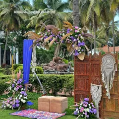 A bohemian-chic photo corner with macrame hangings, pampas grass, and a vibrant blue drape for a pop of color.