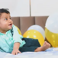A happy baby boy enjoying his birthday balloons. This relaxed, at-home setting allows for natural expressions and comfortable, happy photos.