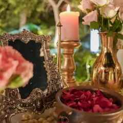 Vintage elegance in a single frame. An ornate silver mirror, a brass candlestick, and a bowl of fresh rose petals create a timeless and romantic corner.