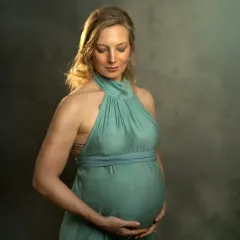 A black and white version of a classic studio portrait. The focus is on the beautiful curves of pregnancy and the mother's gentle, protective gesture.