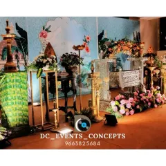 A beautiful traditional cradling ceremony stage. The setup includes ornate brass lamps (diya), a decorated cradle (thottil), and a custom-painted backdrop, blending cultural elements with artistic design.