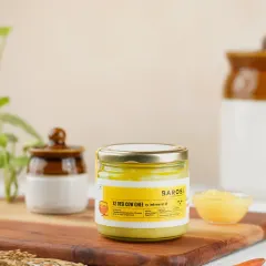 A clean and bright product shot of Barosi's A2 Desi Cow Ghee. The styling with traditional Indian pottery gives it an authentic, farm-fresh feel.