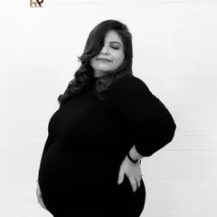 A timeless black and white portrait. The mom-to-be looks confident and beautiful in a simple black dress, her pose highlighting the stunning curves of pregnancy.