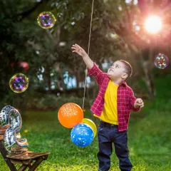 A little boy reaches for bubbles in a sun-drenched park. This action shot perfectly captures the wonder and joy of a child playing outdoors.
