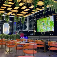 A modern restaurant interior with hanging greenery from a grid ceiling and sleek planters. The artificial plants soften the industrial design and add a layer of sophistication.