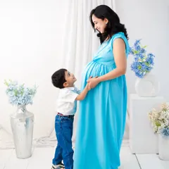 A tender moment between mother and son. The older brother looks up at his mother with adoration, his hand gently on her belly. It's a quiet, beautiful portrait of the bond they share and the new one they will soon have.