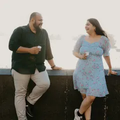 A relaxed moment of a couple leaning against a wall overlooking the Mumbai sea link, laughing and enjoying a cup of chai. This shows how we can capture casual, everyday romance.