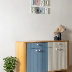 This custom fluted crockery unit, painted in pastel blue and ivory, adds elegant charm to the dining space. Above it, custom ceramic artwork ties together the home's overall pastel theme.