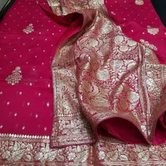 A classic red Banarasi saree, laid out to show its magnificent zari work on the border and pallu. This piece is a must have for any bridal trousseau or major festive event, offering a look of pure opulence.