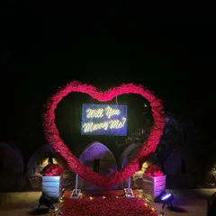 A slightly different view of the grand rose heart proposal decoration. The setup includes a rose petal-covered walkway and is perfect for a dramatic outdoor evening proposal.