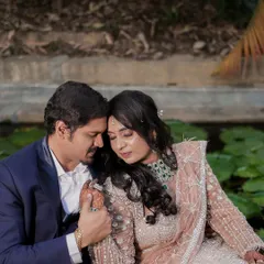 An intimate and tender close-up of a couple in formal Indian attire, sharing a quiet moment by a lily pond.