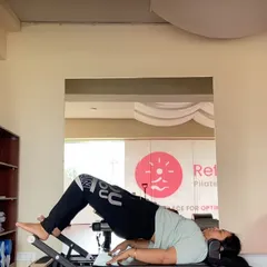 A client performs a glute bridge on the reformer, an excellent exercise for activating the posterior chain and strengthening the lower back in a supported way. This is a key move for improving posture.
