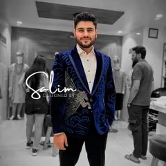 A client wearing a custom blue velvet tuxedo jacket. The design features a hand-embroidered Pegasus and wave-like patterns, blending classic tailoring with mythical artistry.