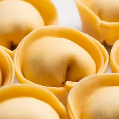 An extreme close-up of fresh tortelloni. This macro view reveals the delicate shape and texture of the handmade pasta.